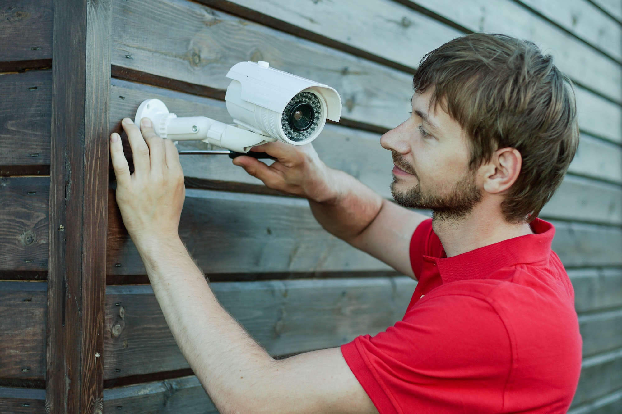 Caucasian technician installing IP wireless CCTV camera by screwed for home security system